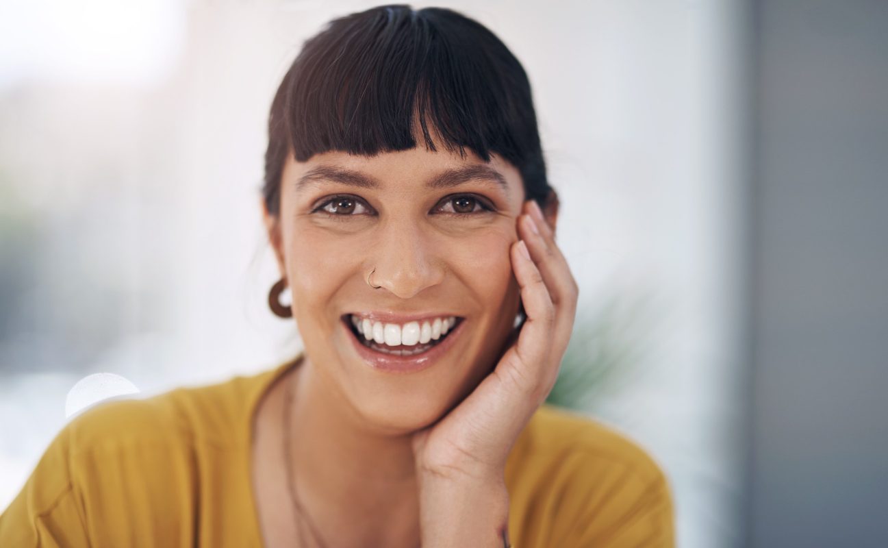 Mujer en edad adulta con una sonrisa y playera color mostaza.